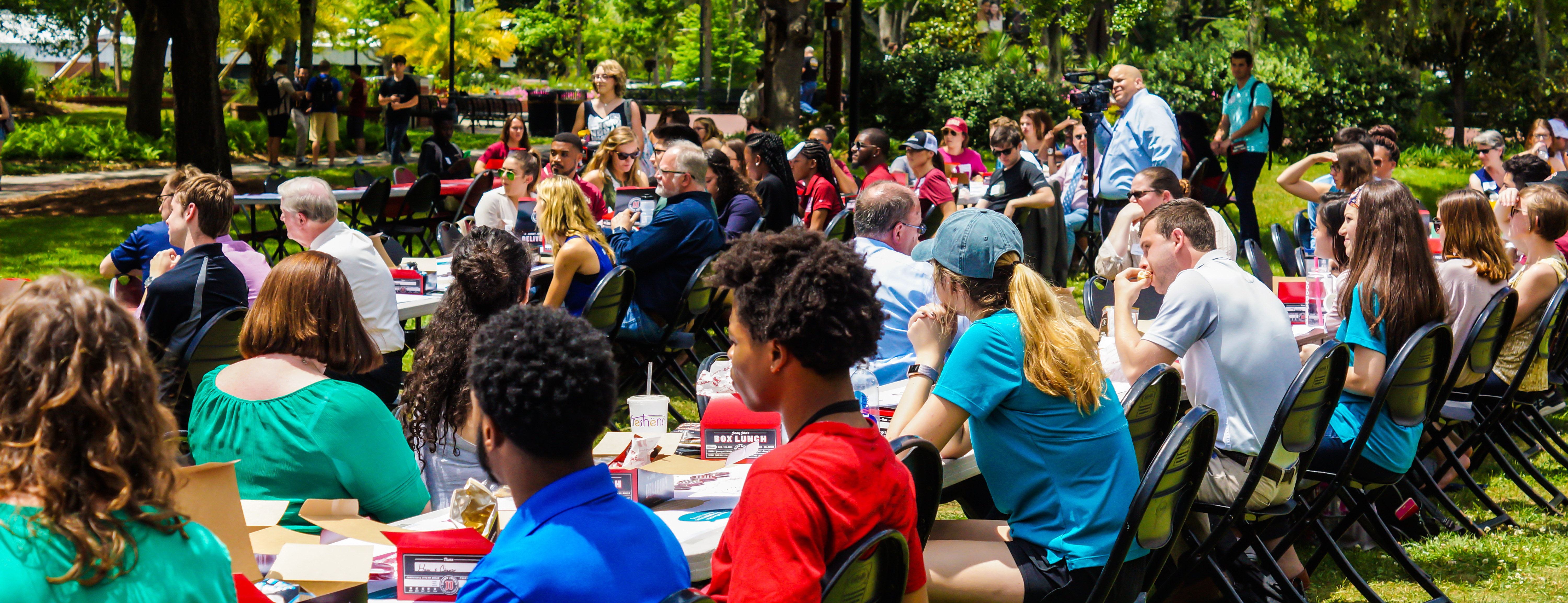 Photo of students gathered at tables on the Union Green for a Power of We event